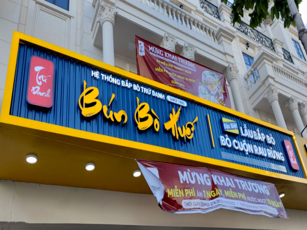 A colorful Vietnamese neon sign on a bustling street in Hanoi or Saigon