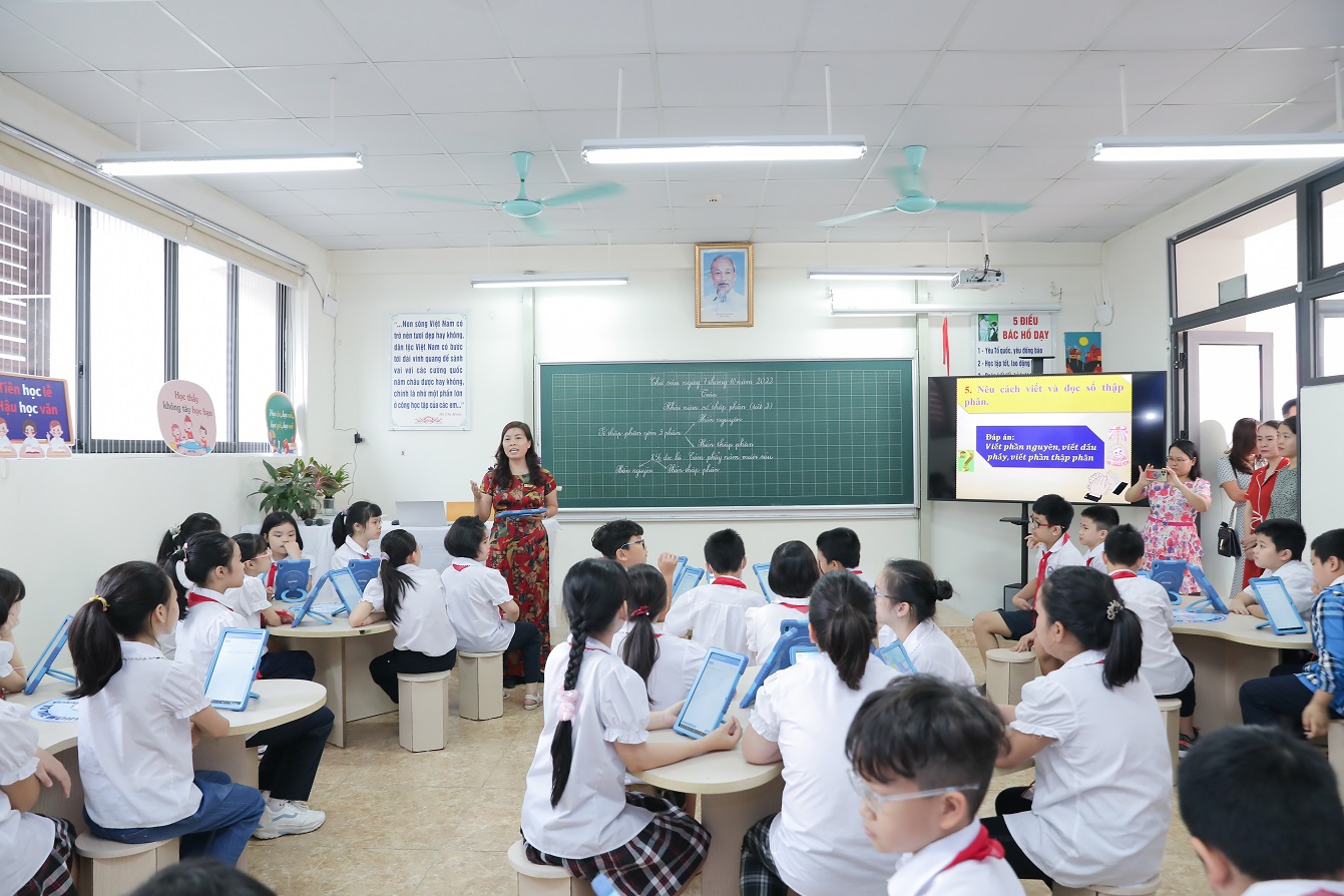 Vietnamese students in a classroom—attentive, in uniform, with a traditional chalkboard