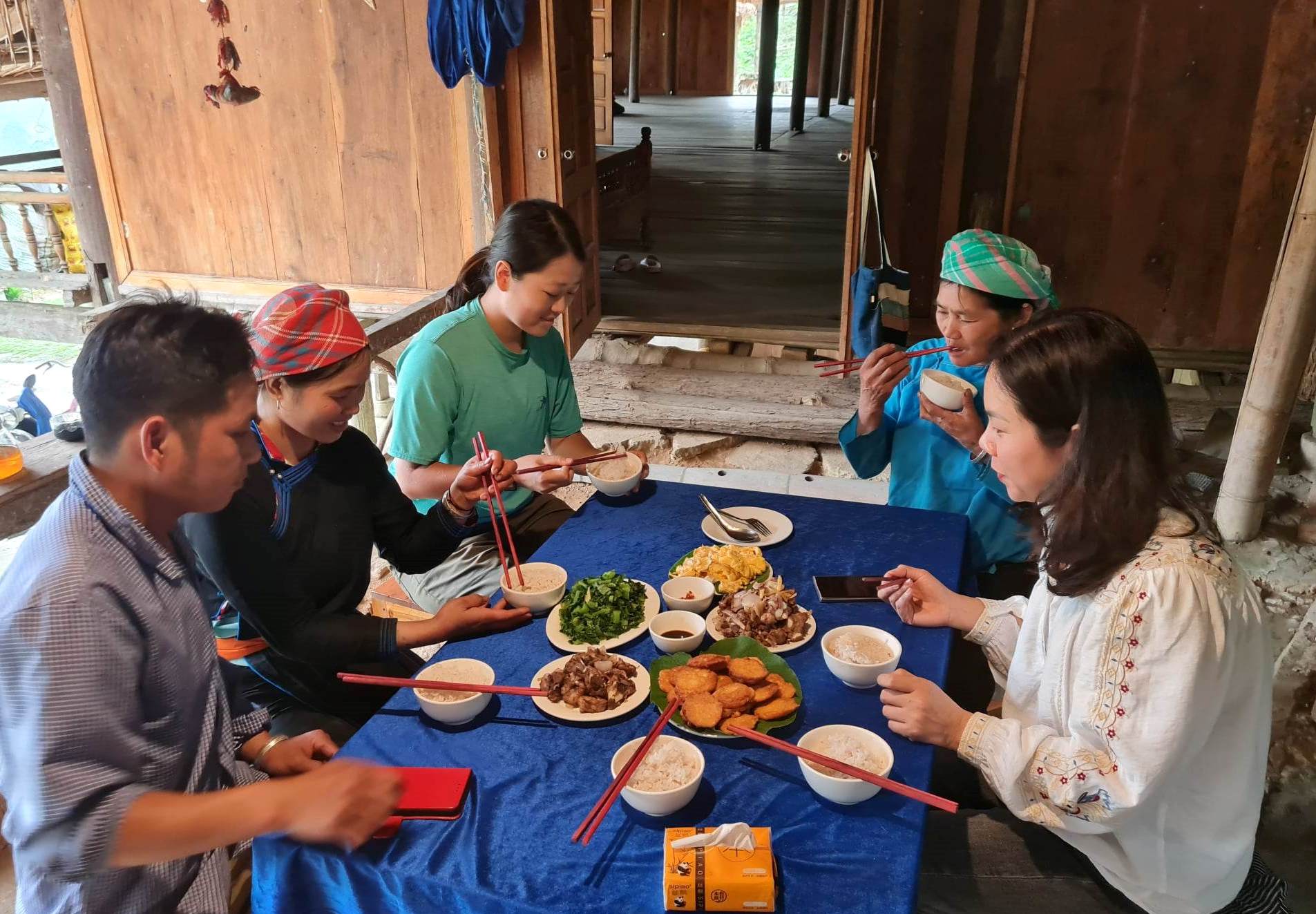 Tourists at a homestay with an ethnic minority family, sharing a communal dinner