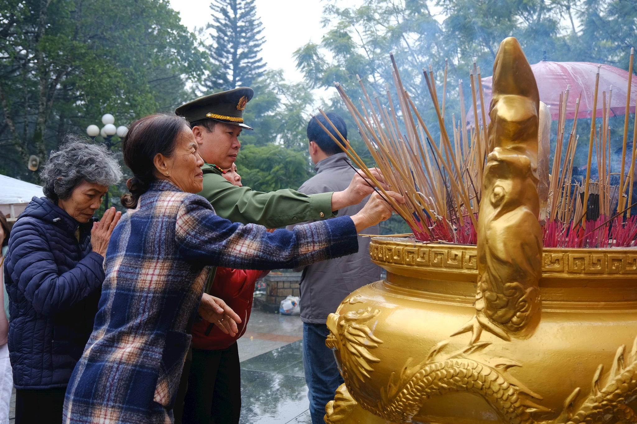 A memorial incense-lighting ritual — a Vietnamese family at an ancestral altar or a cemetery