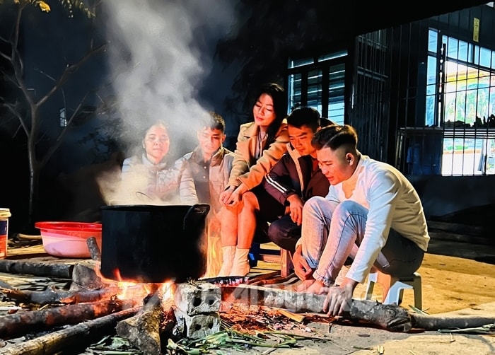 Vietnamese women boiling bánh chưng over an open wood fire in massive pots