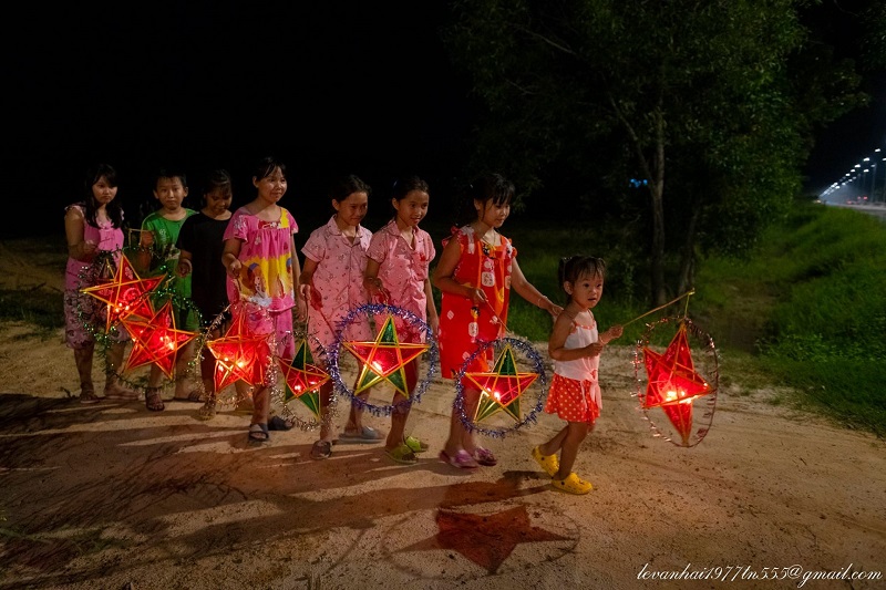 Children parading with Vietnamese star lanterns on Mid-Autumn night — 5-pointed star lanterns in red and yellow