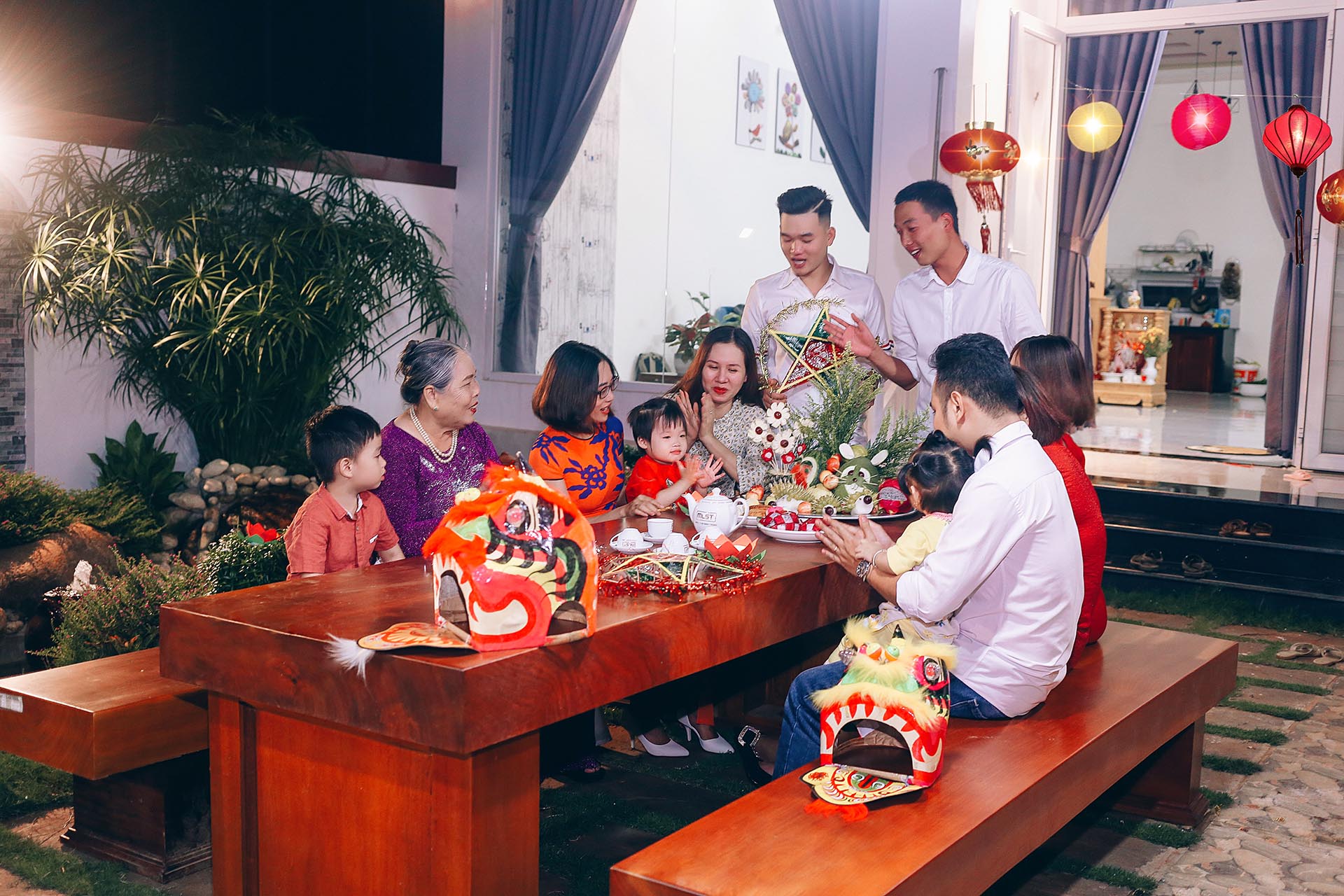 A Vietnamese family sitting together admiring the Mid-Autumn moon — adults and children alike