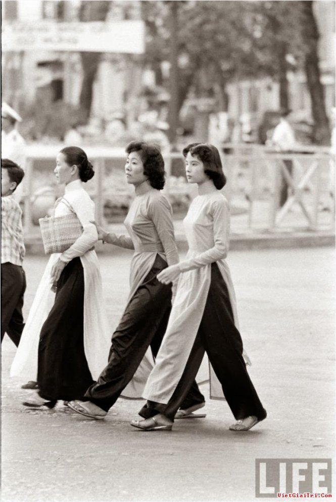 Black and white photograph of Saigon women in the 1960s wearing Áo Dài while walking down the street
