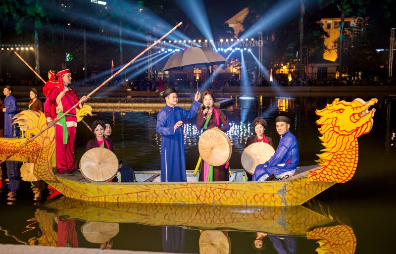 Singing quan họ on a boat in a village pond — women wearing traditional multi-layered dresses (áo mớ ba mớ bảy), singing antiphonally