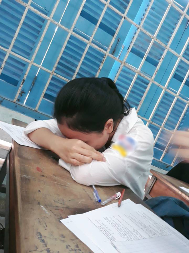 An exhausted Vietnamese student resting their head on their study desk