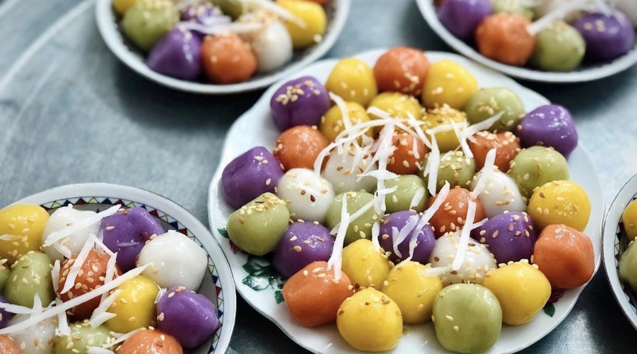 A vibrantly colored plate of Vietnamese food — red tomatoes, green vegetables, yellow turmeric, white bean sprouts, black mushrooms