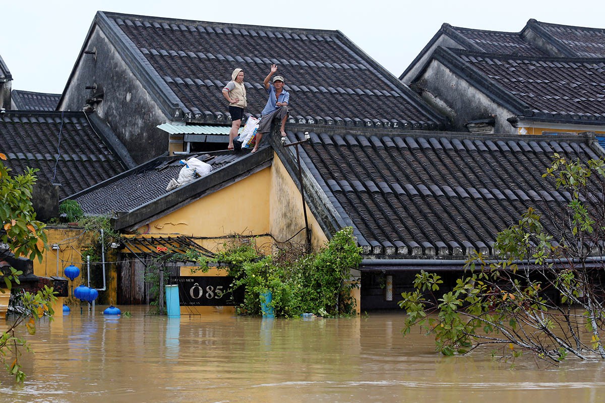 Central Vietnamese houses submerged in floodwaters — residents navigating through the neighborhood in small boats — yet remaining calm and operational