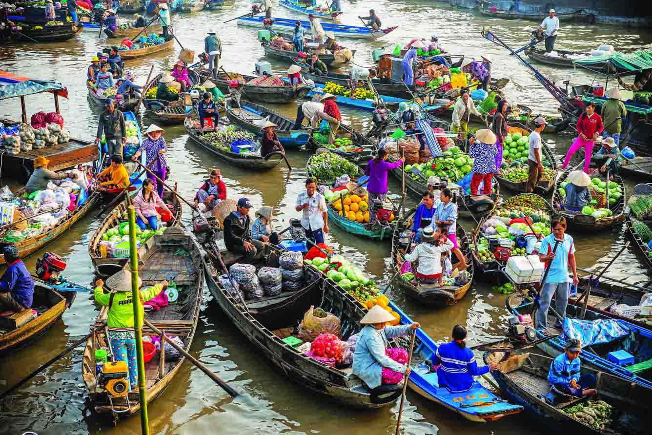 Cai Be or Cai Rang floating market — boats packed tightly together, vibrant tropical fruit, dynamic early morning trading