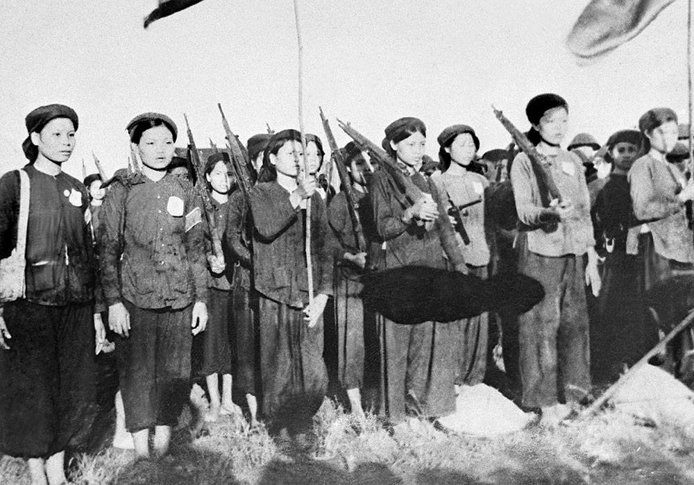 Vietnamese women operating during wartime — carrying rifles or hauling supplies through the jungle — black and white historical imagery
