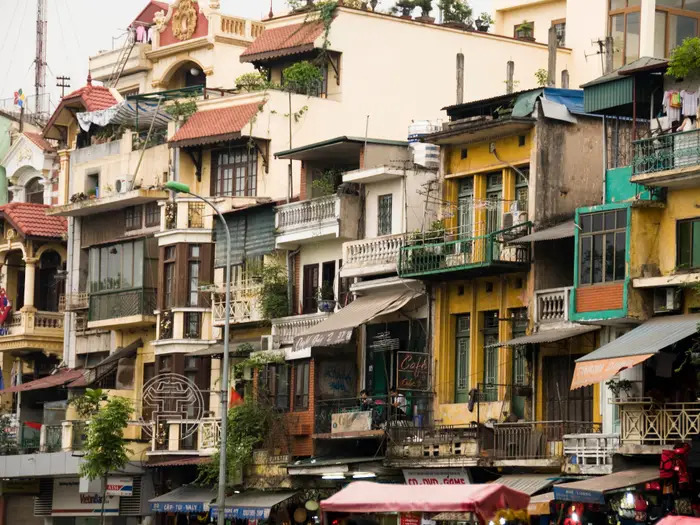 A dense row of Hanoi or Saigon tube houses — impossibly narrow, tall, and highly vibrant adjacent to one another