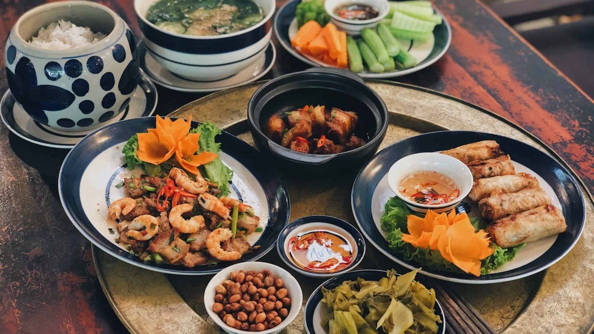 A Vietnamese family meal welcoming a guest — a table packed with dishes, everyone sitting around it