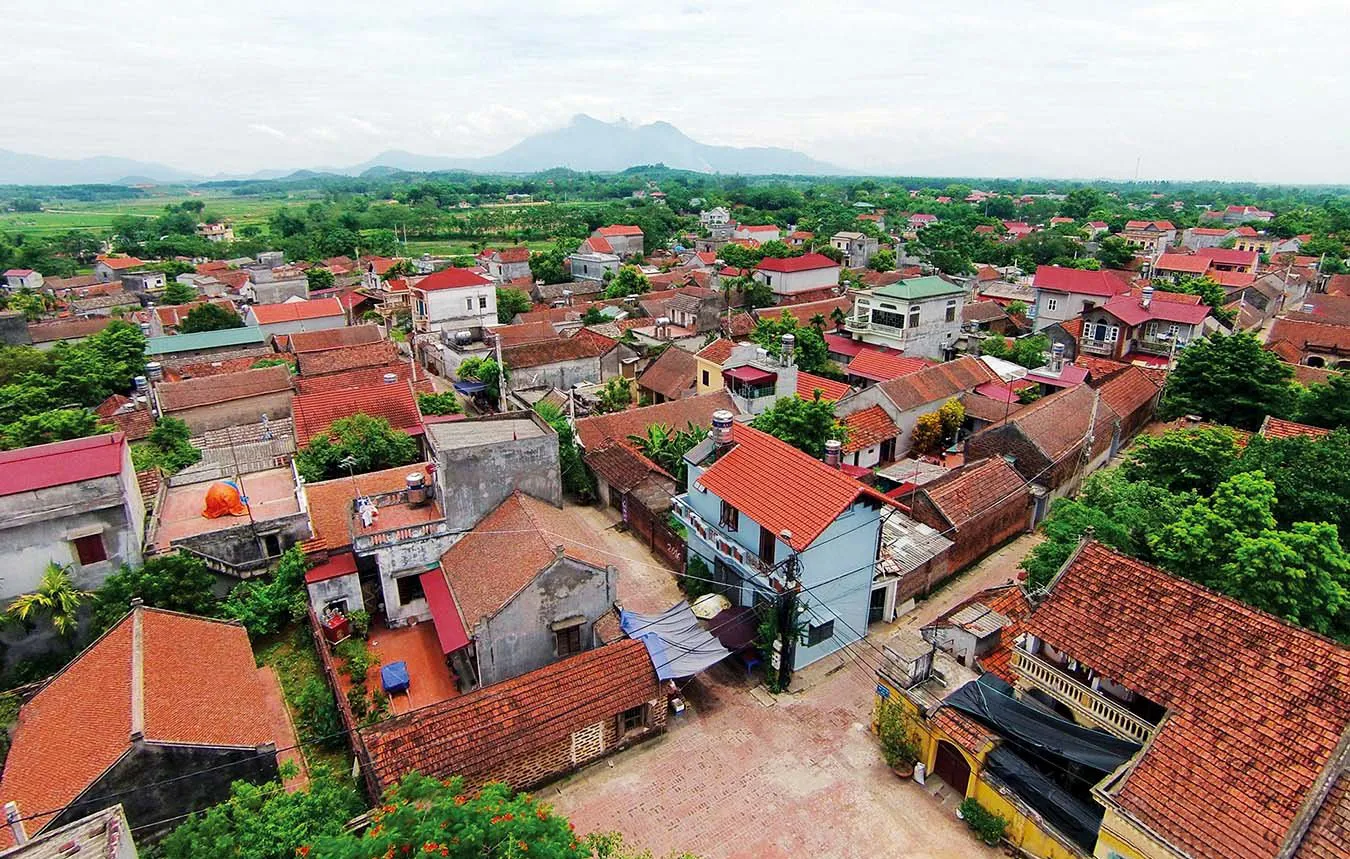 The extreme contrast of urban-rural Vietnam — massive skyscrapers in Saigon juxtaposed against a quiet village